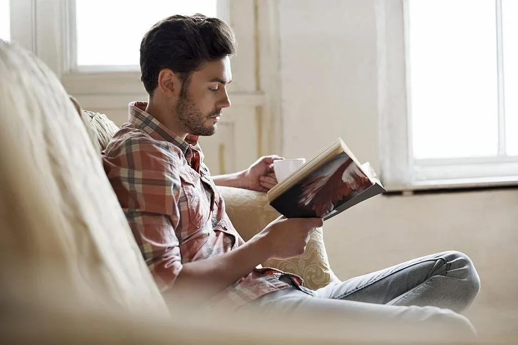 a man sitting on a couch reading a book