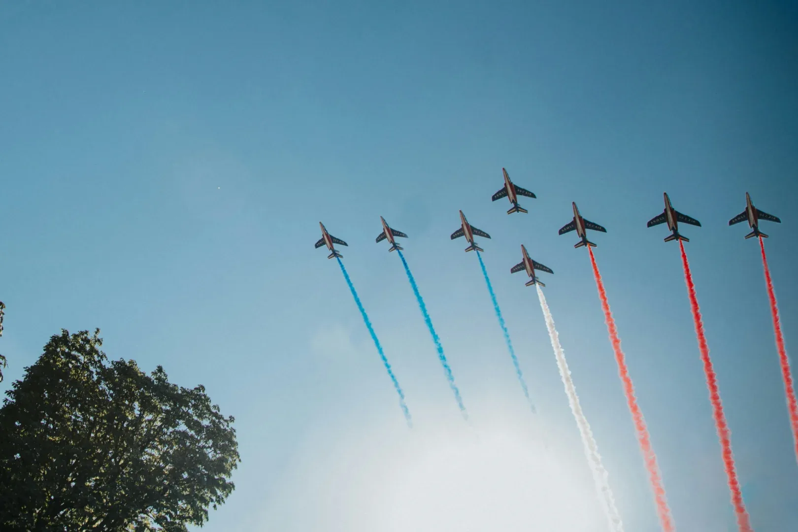 a group of airplanes flying in the sky with smoke trails